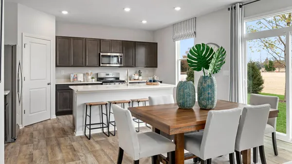 a dining room with furniture a potted plant and kitchen view