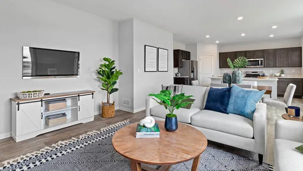 a living room with furniture potted plant and kitchen view