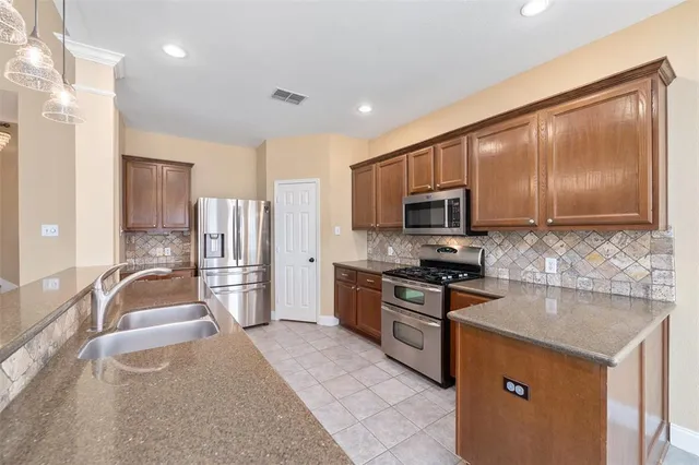 a kitchen with stainless steel appliances granite countertop a sink stove and refrigerator