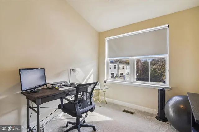 a view of a workspace with furniture and a window