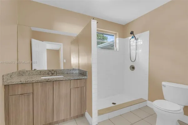 a bathroom with a granite countertop sink a mirror and a toilet