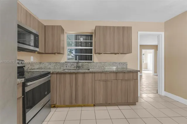 a kitchen with granite countertop a stove a sink and a microwave