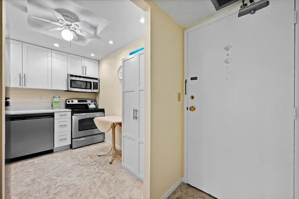 a kitchen with stainless steel appliances granite countertop white cabinets and refrigerator