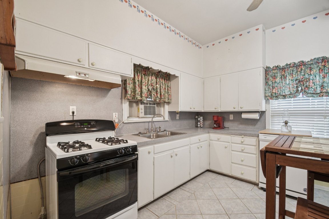 611 North Main Street Elgin, TX 78621 - Photo 19 of 34 Kitchen with range with gas cooktop, light countertops, light tile patterned floors, and white cabinetry