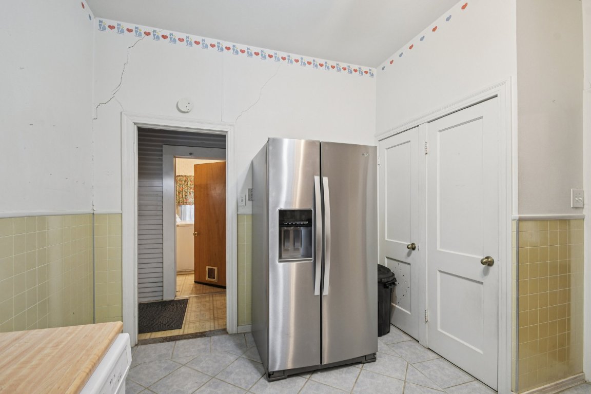 611 North Main Street Elgin, TX 78621 - Photo 21 of 34 Kitchen with tile walls, stainless steel fridge with ice dispenser, a wainscoted wall, and light tile patterned flooring
