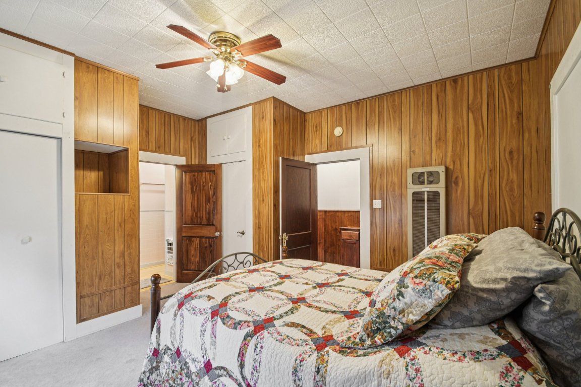 611 North Main Street Elgin, TX 78621 - Photo 23 of 34 Carpeted bedroom featuring wood walls and a ceiling fan