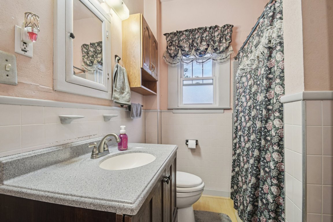 611 North Main Street Elgin, TX 78621 - Photo 28 of 34 Full bath featuring tile walls, a wainscoted wall, vanity, a stall shower, and light wood-type flooring
