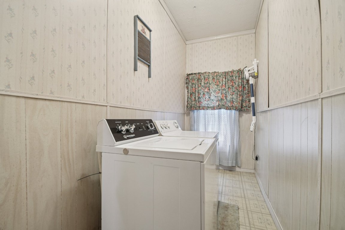 611 North Main Street Elgin, TX 78621 - Photo 29 of 34 Laundry room with a wainscoted wall, crown molding, light flooring, wood walls, and washing machine and clothes dryer