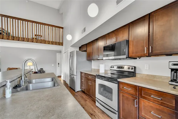 a kitchen with stainless steel appliances granite countertop a sink dishwasher stove and microwave with wooden cabinets