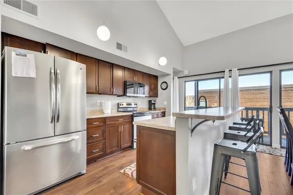 a kitchen with stainless steel appliances granite countertop a refrigerator a stove top oven a sink dishwasher and white cabinets with wooden floor