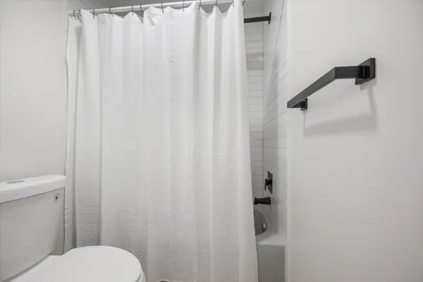 a white toilet sitting next to a shower curtain