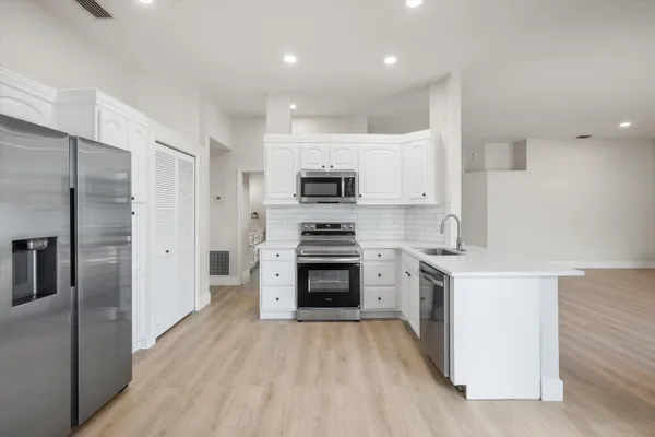 a kitchen with granite countertop a stove top oven and refrigerator