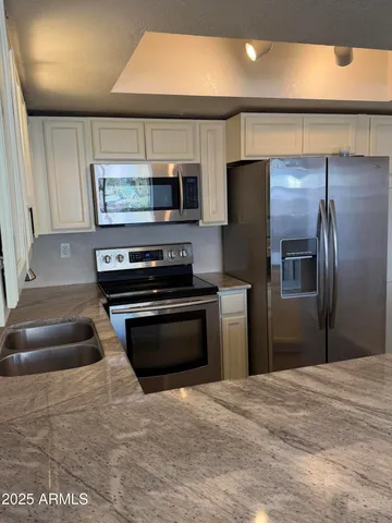 a kitchen with stainless steel appliances kitchen island granite countertop a refrigerator and a stove
