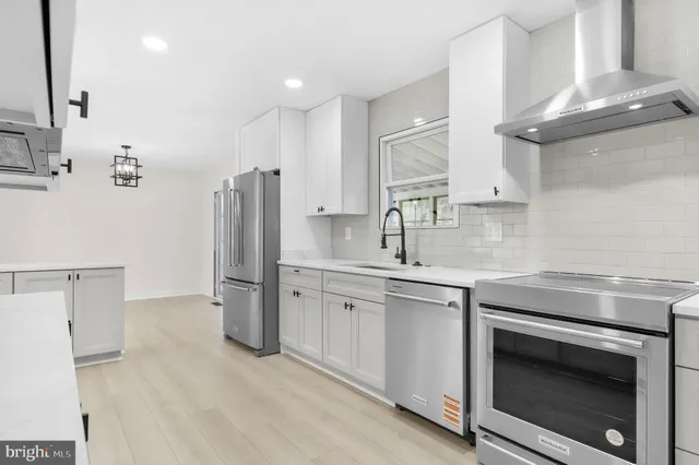 a large kitchen with stainless steel appliances kitchen island a refrigerator and a stove