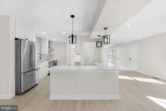 a large kitchen with kitchen island a stove a sink a center island and wooden floor