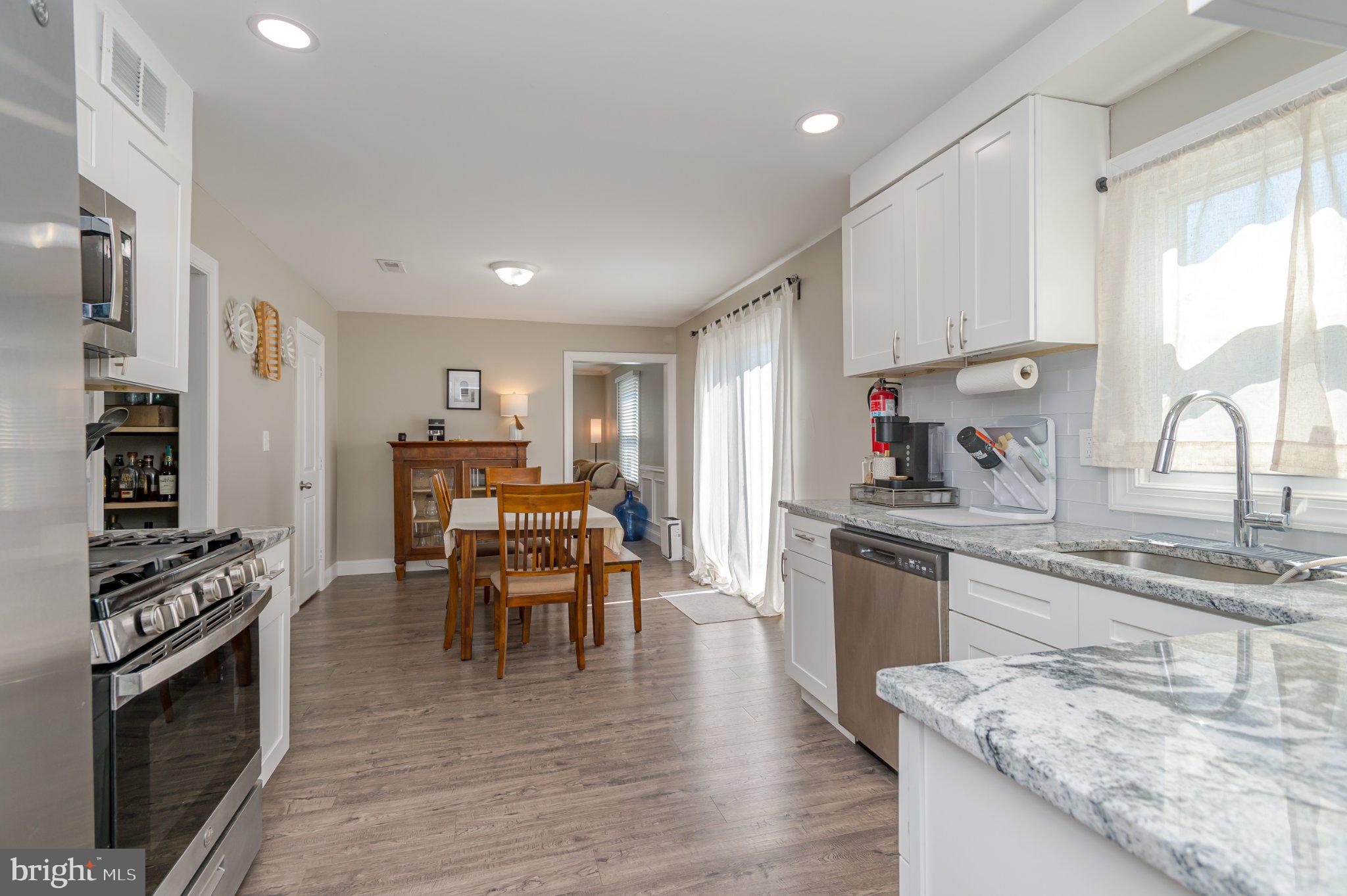 60 Midvale Lane Willingboro, NJ 08046 - Photo 11 of 24 a kitchen with stainless steel appliances granite countertop a stove top oven a sink dishwasher a dining table and chairs with wooden floor