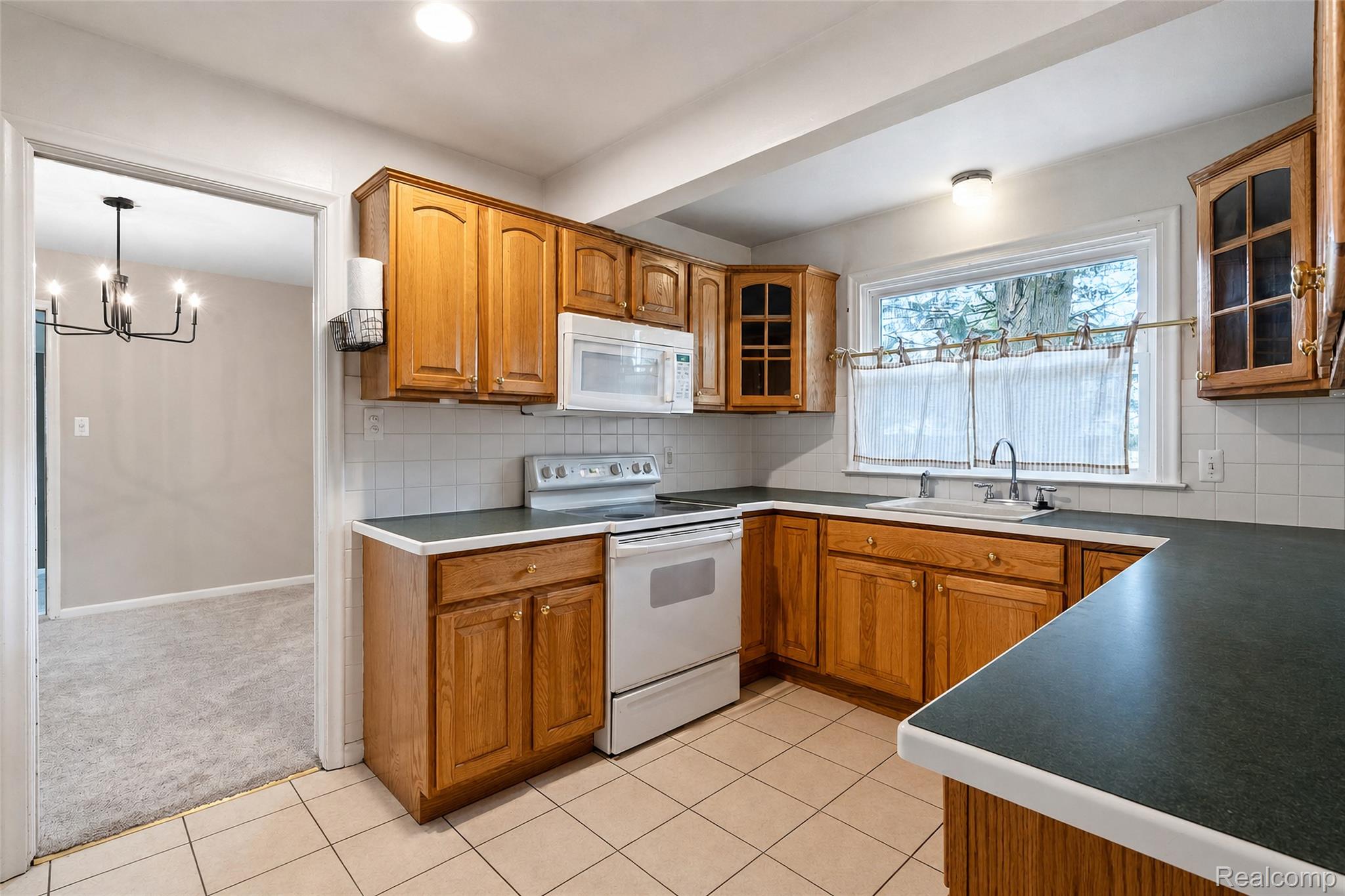 1846 Pembroke Road Birmingham, MI 48009 - Photo 24 of 37 Kitchen featuring wood cabinetry, white tile backsplash, a window over the sink, and tile flooring