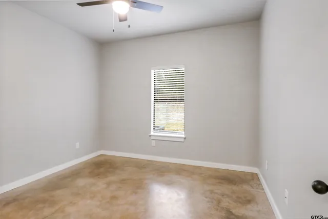 an empty room with a chandelier fan and windows