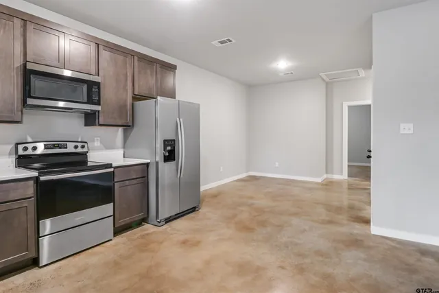 a kitchen with stainless steel appliances granite countertop a stove a refrigerator and a microwave