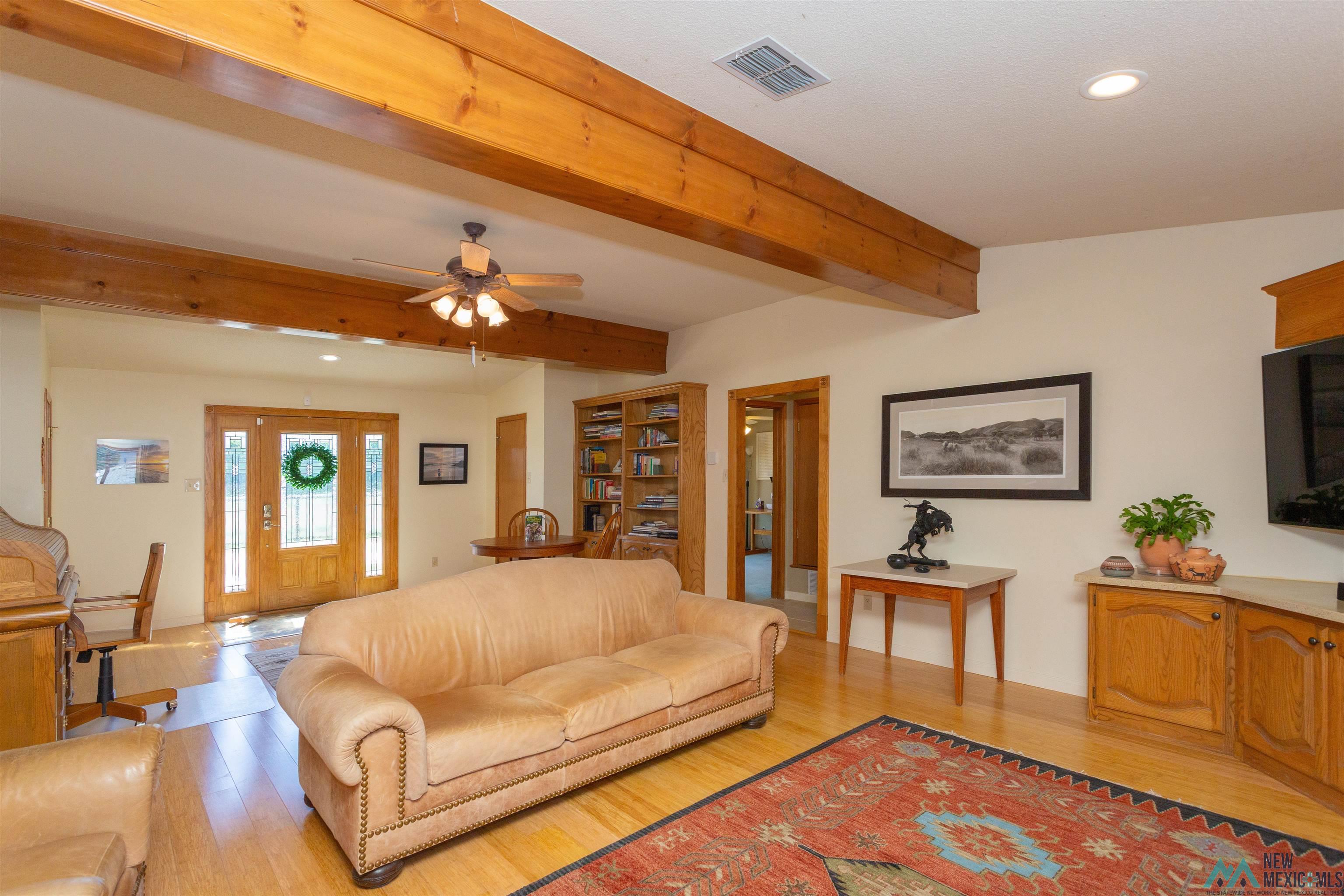 2012 South Haldeman Road Artesia, NM 88210 - Photo 14 of 96 Exposed wood beams accentuating the ceiling, wood-finish flooring throughout, a double entry door with decorative glass inserts, recessed lighting, and a built-in entertainment center with wood cabinetry and a light-toned countertop