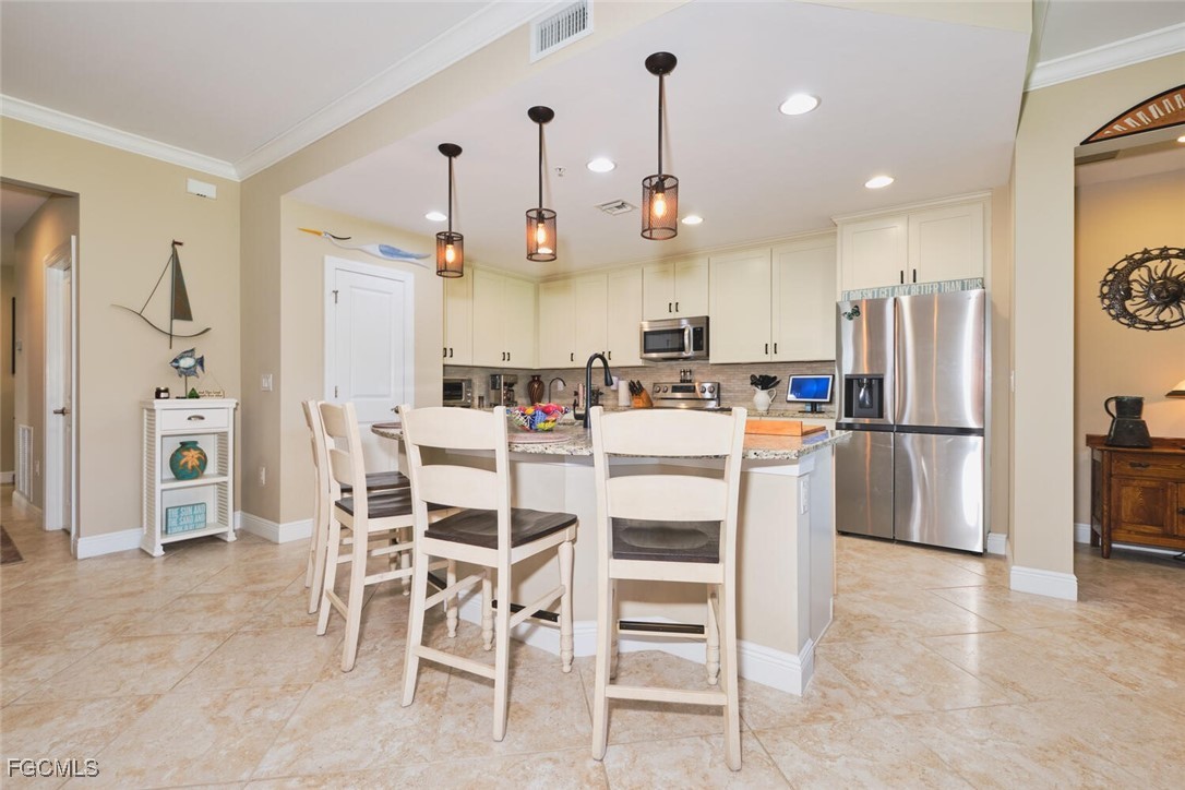 11856 Arboretum Run Drive, Unit 102 Fort Myers, FL 33913 - Photo 13 of 47 a kitchen with stainless steel appliances kitchen island granite countertop a refrigerator and a stove top oven