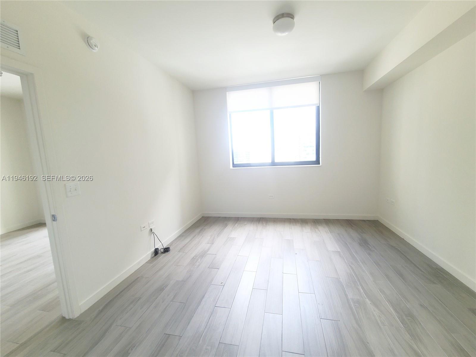 999 Southwest 1st Avenue, Unit 1808 Miami, FL 33130 - Photo 11 of 16 an empty room with wooden floor and windows