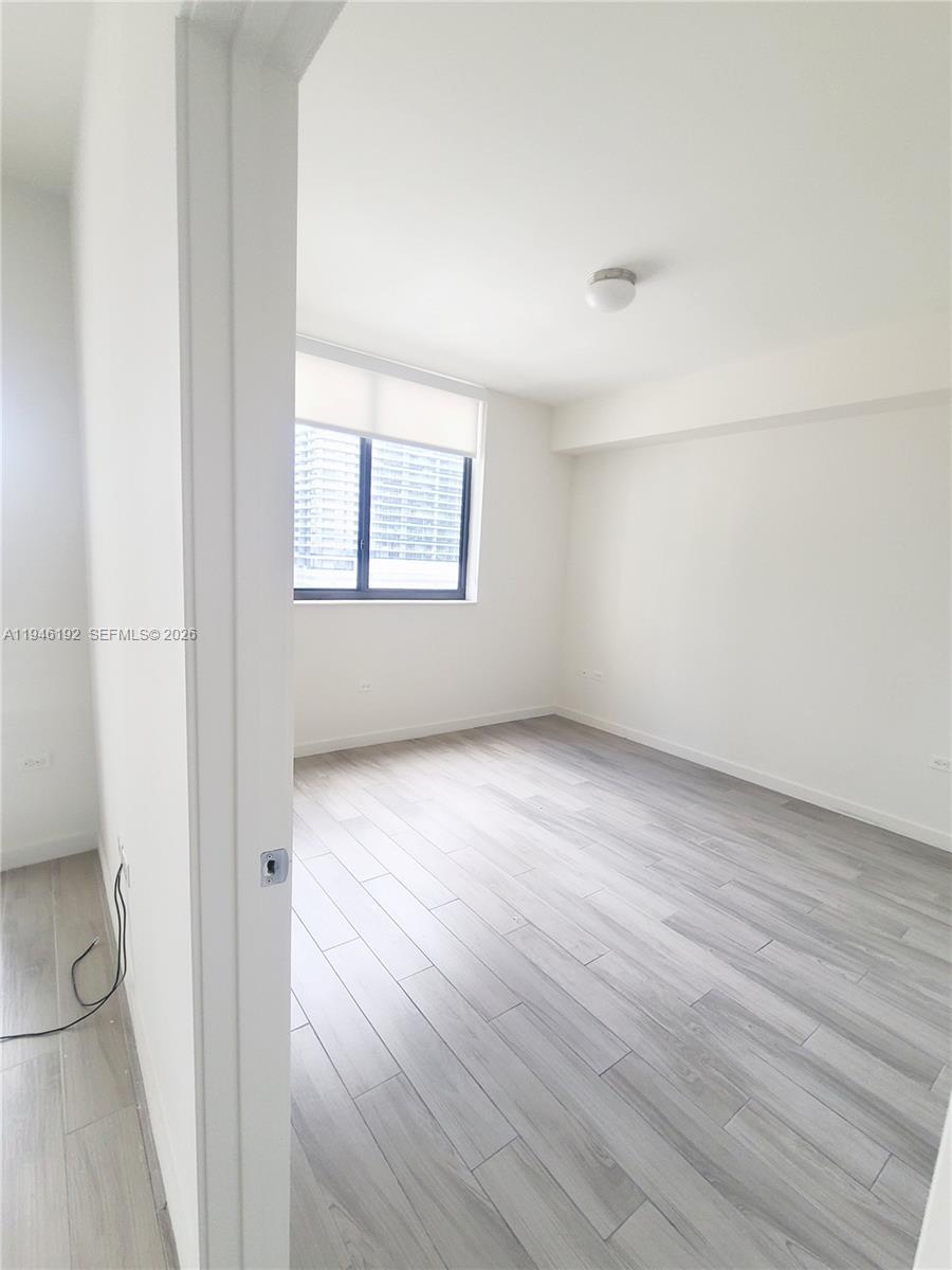 999 Southwest 1st Avenue, Unit 1808 Miami, FL 33130 - Photo 12 of 16 an empty room with wooden floor and windows