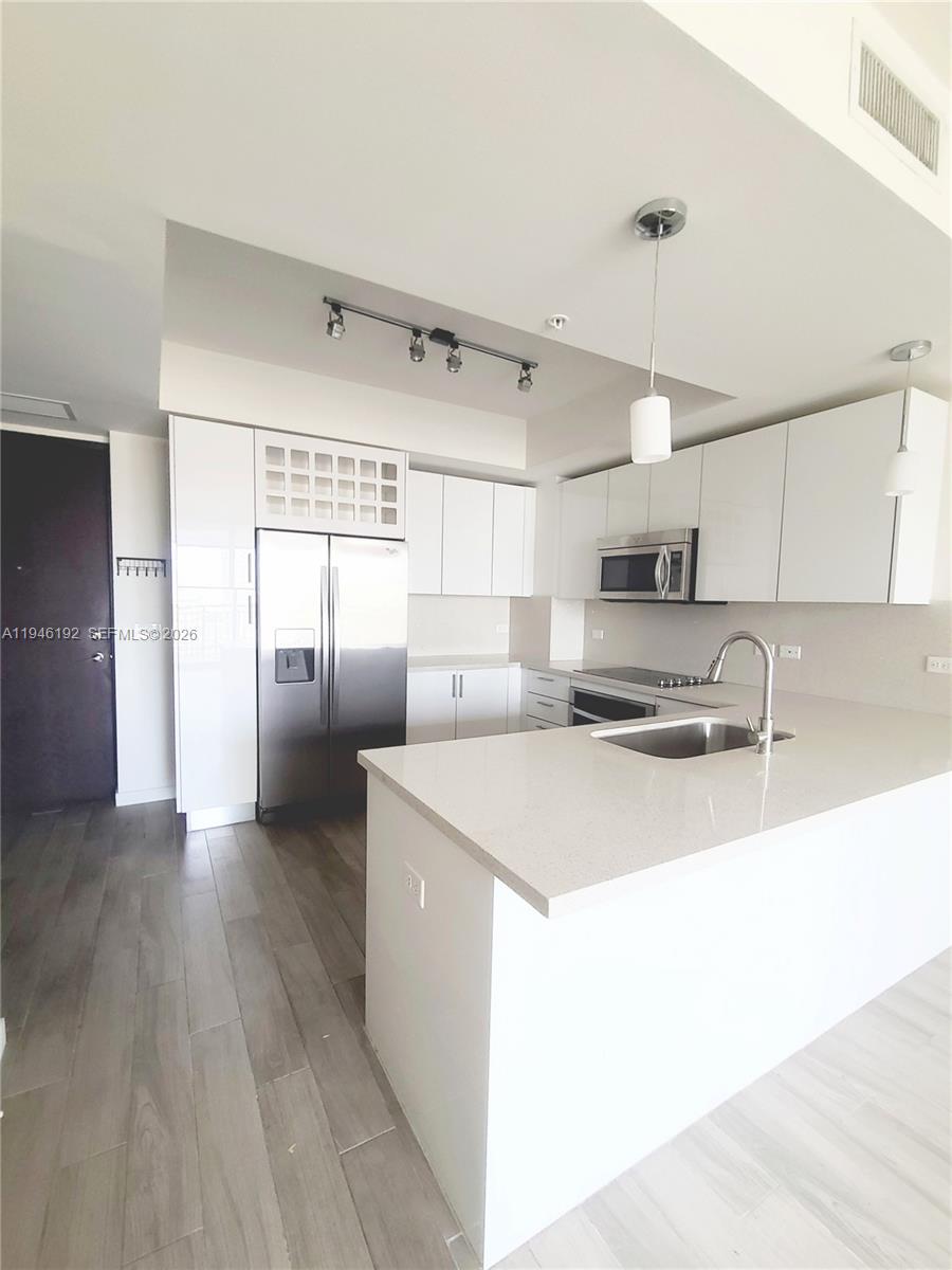 999 Southwest 1st Avenue, Unit 1808 Miami, FL 33130 - Photo 9 of 16 a kitchen with stainless steel appliances granite countertop a sink and a refrigerator
