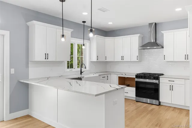 a kitchen with stainless steel appliances a refrigerator a sink dishwasher a stove and white cabinets with wooden floor