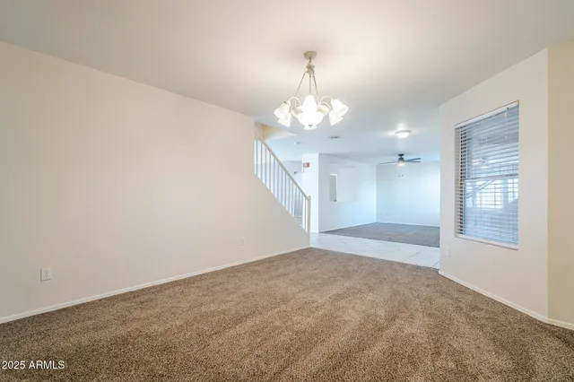 an empty room with ceiling fan and windows