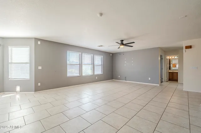 an empty room with a ceiling fan and window