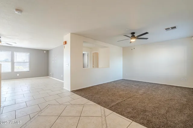 an empty room with windows and chandelier fan