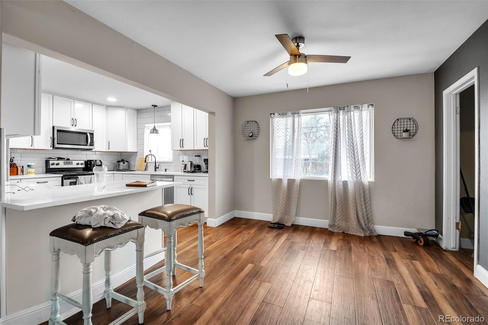 840 Tucson Street Aurora, CO 80011 - Photo 5 of 29 a kitchen with stainless steel appliances granite countertop a stove top oven a refrigerator a sink a dining table and chairs with wooden floor