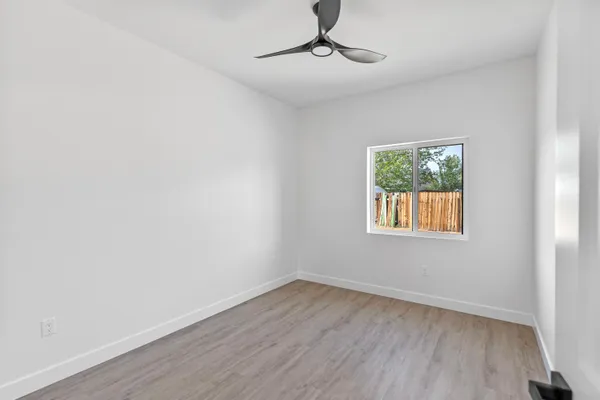 a view of an empty room with wooden floor and a window
