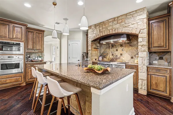a kitchen with stainless steel appliances granite countertop a kitchen island a stove a table and chairs in it