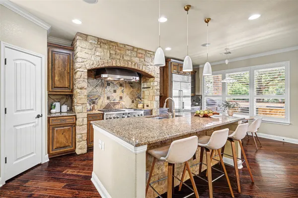a kitchen with stainless steel appliances granite countertop a table chairs sink and wooden floor