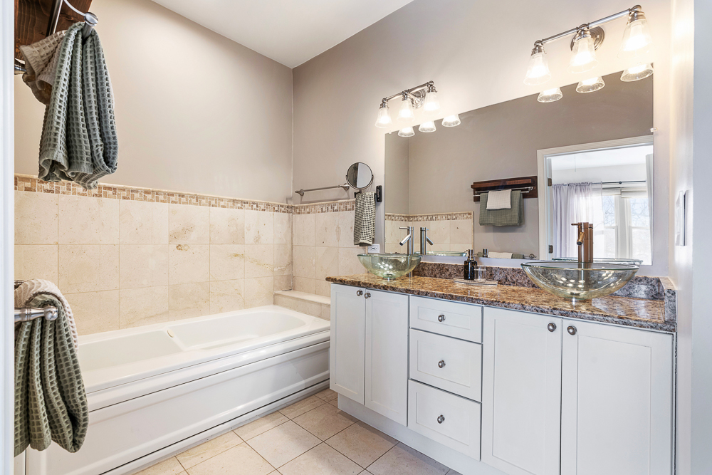 1002 West Altgeld Street, Unit 1002 Chicago, IL 60614 - Photo 17 of 39 a bathroom with a granite countertop bathtub sink and mirror