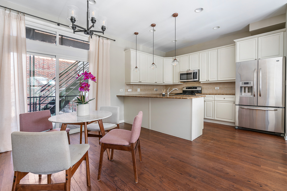 1002 West Altgeld Street, Unit 1002 Chicago, IL 60614 - Photo 9 of 39 a kitchen with stainless steel appliances granite countertop a stove a refrigerator a kitchen island a dining table and chairs with wooden floor