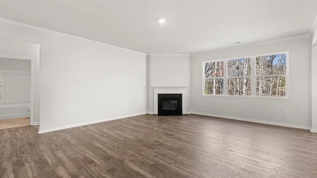 an empty room with wooden floor fireplace and windows