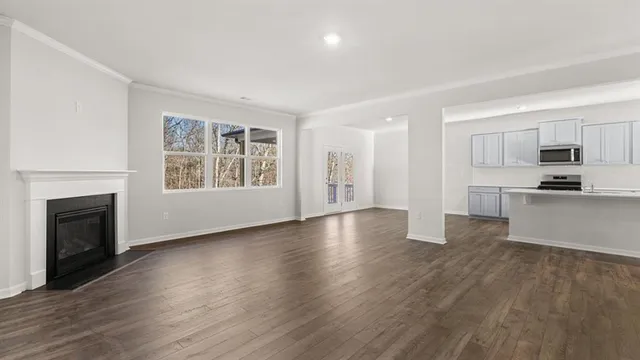a view of a kitchen and an empty room with wooden floor a fireplace