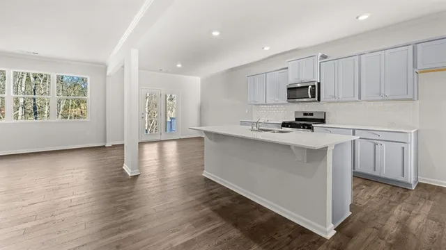 a kitchen with stainless steel appliances a white stove top oven a sink a window and white cabinets