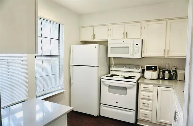 a kitchen with white cabinets and white appliances