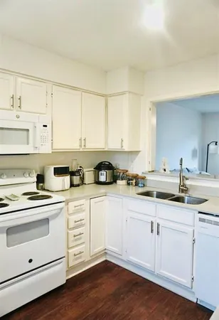 a white kitchen with sink and cabinets