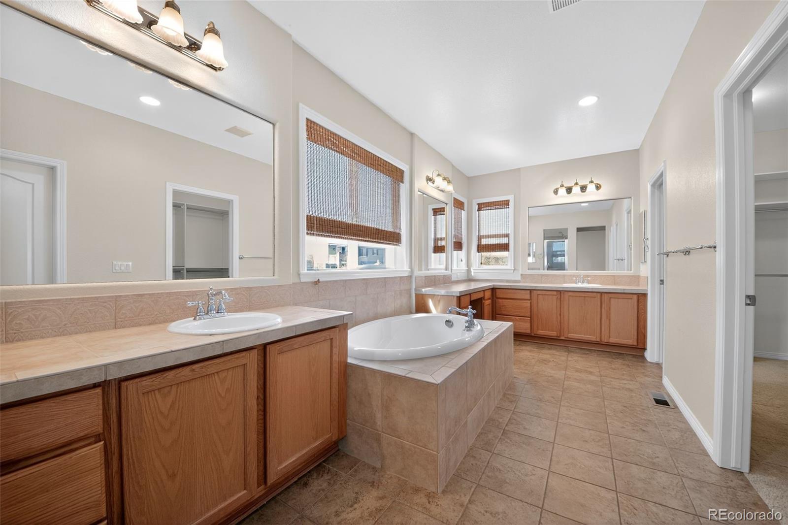 11036 Glengate Circle Highlands Ranch, CO 80130 - Photo 27 of 31 a spacious bathroom with a double vanity sink a mirror and a bathtub