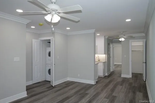 a view of an empty room with wooden floor and a ceiling fan