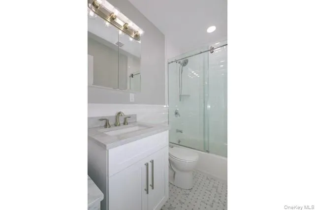 a bathroom with a granite countertop sink a toilet and a shower