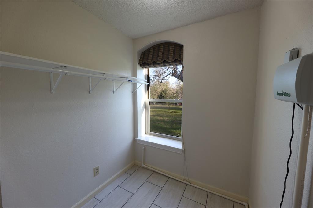 907 Red Oak Creek Road Ovilla, TX 75154 - Photo 19 of 20 Compact utility space featuring a rectangular window with an arched top, tile flooring, and wall-mounted shelving