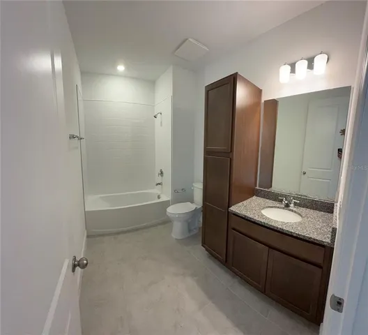 a bathroom with a granite countertop sink a toilet and shower