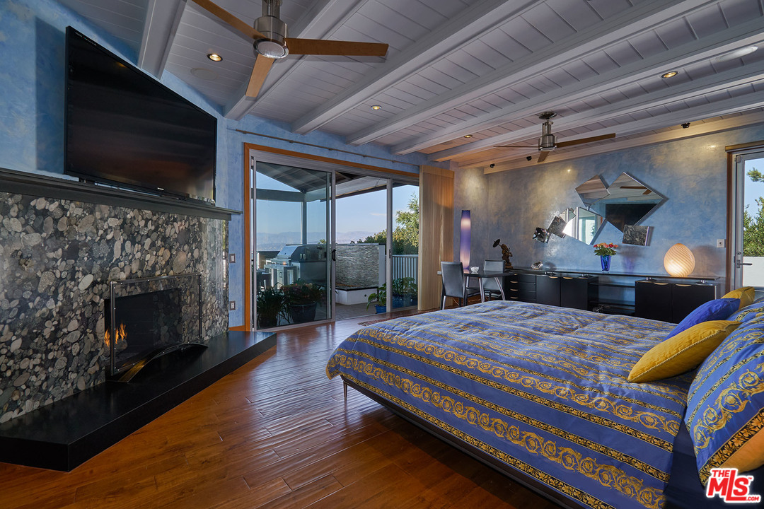 8647 Edwin Drive Los Angeles, CA 90046 - Photo 11 of 32 a bedroom with a bed a flat screen tv and a fireplace
