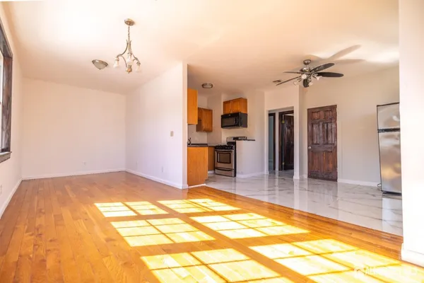 a view of a livingroom with a chandelier fan and kitchen view